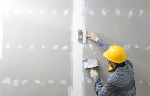 interior decoration construction furniture builtin.Plasterer in working uniform plastering the wall indoors.